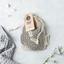 Mesh cotton bag containing 10 Ever Eco black reusable make up pads with a tag on a light gray background with flowers