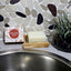 Dishwashing block on a soap dish with a decorative stone wall in the background