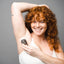 lady with red curly hair smiling into camera raising right arm above head applying woohoo body deodorant and anti-chafe stick tux extra strength 60 grams