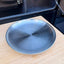 Kids brushed stainless steel double wall plate with the brand name 'INDISPOSABLE' in the center, resting on a light wood cutting board on a camper van.