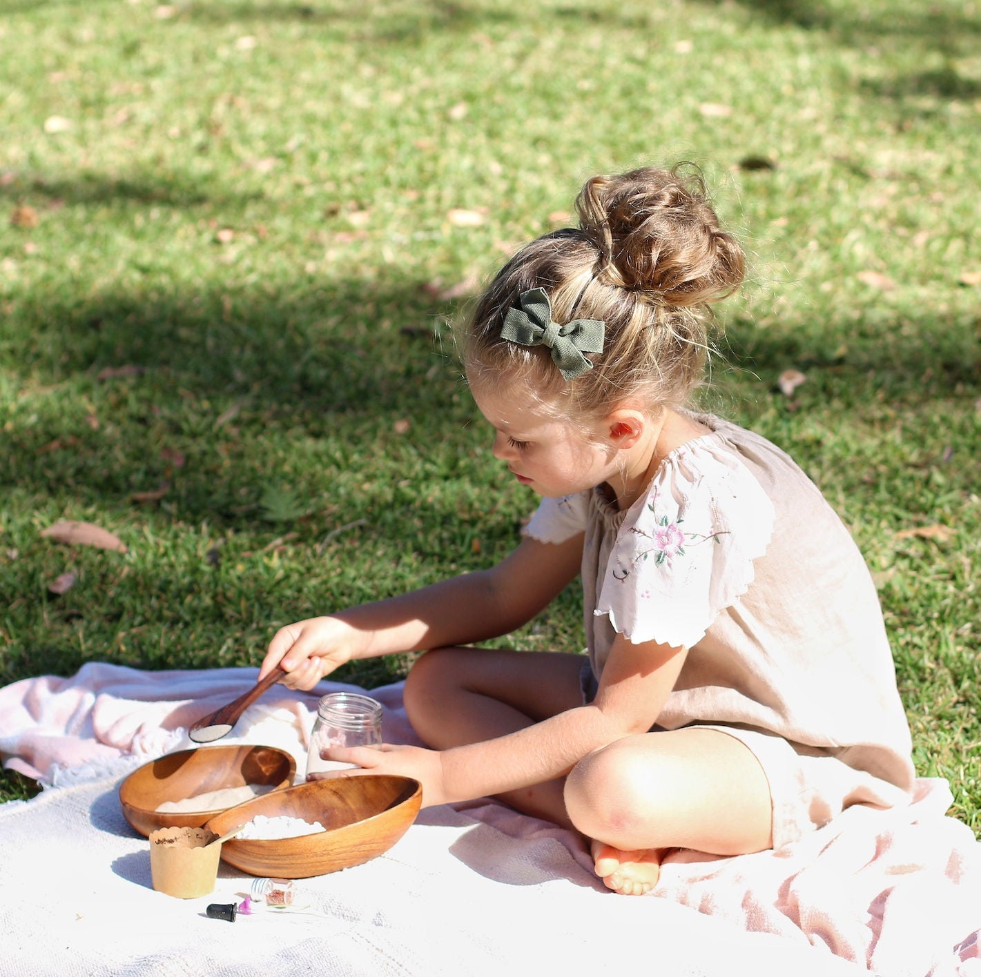 Poppy and daisy mini fairy garden kit being completed by girl sitting on picnic rug on grass