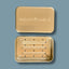 Travel soap tin with drainage tray with 'INDISPOSABLE' branding on a blue background