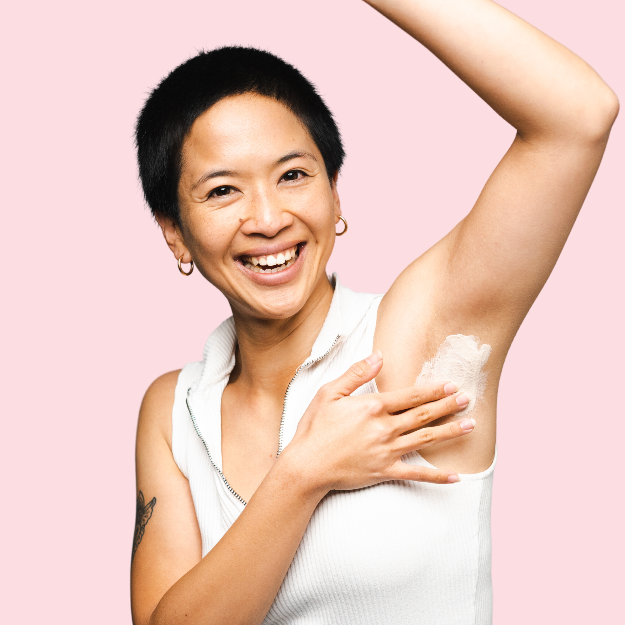 lady smiling at camera with left arm raised over her head applying woohoo armpit detox mask to armpit