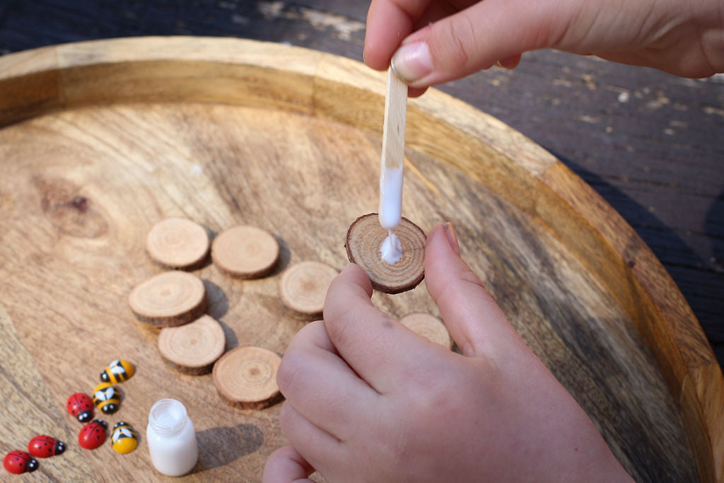 Child's hands placing glue onto wooden chip